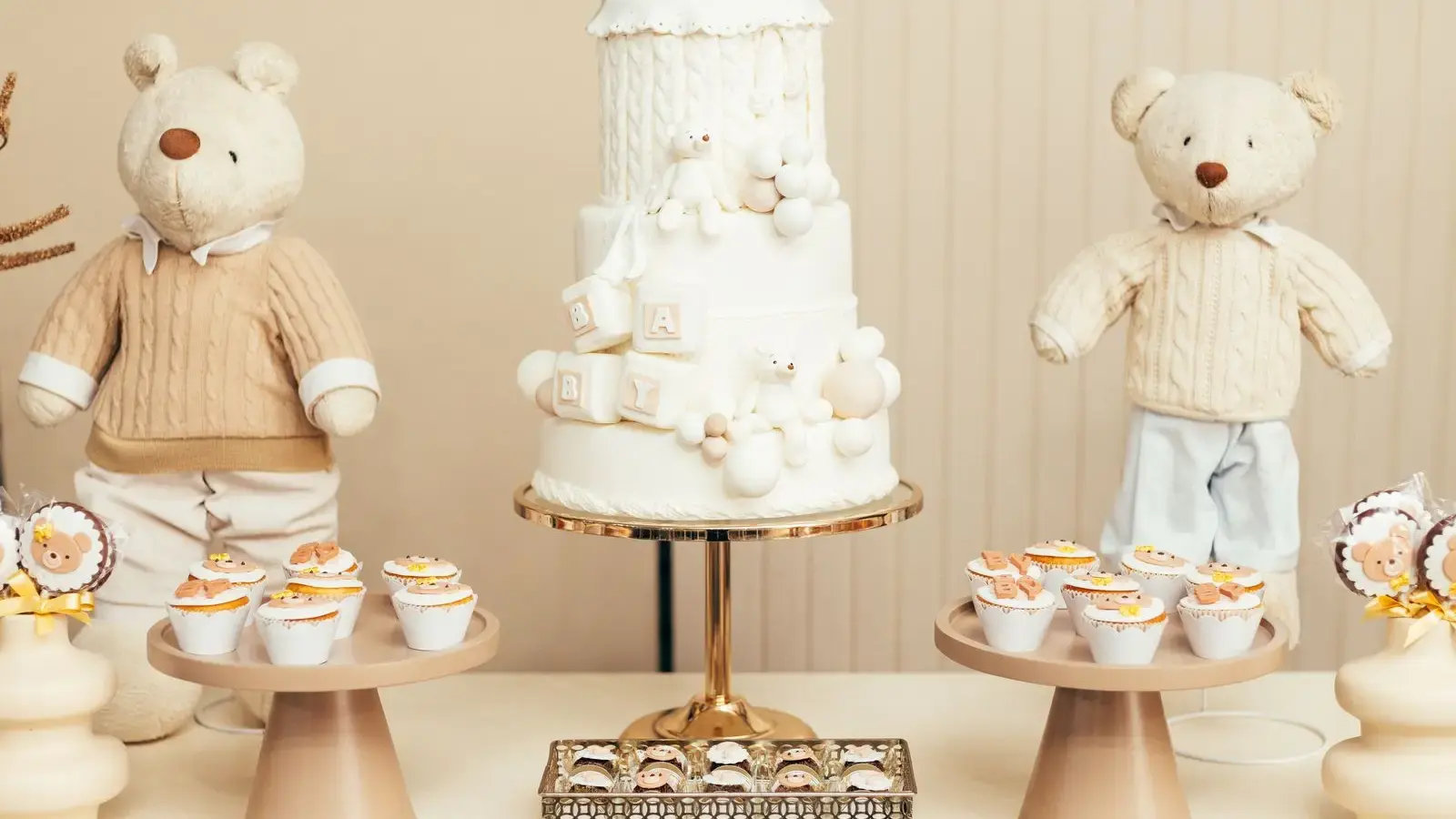 Mesa dulce de baby shower con tarta blanca de tres pisos y ositos de peluche con jersey de punto